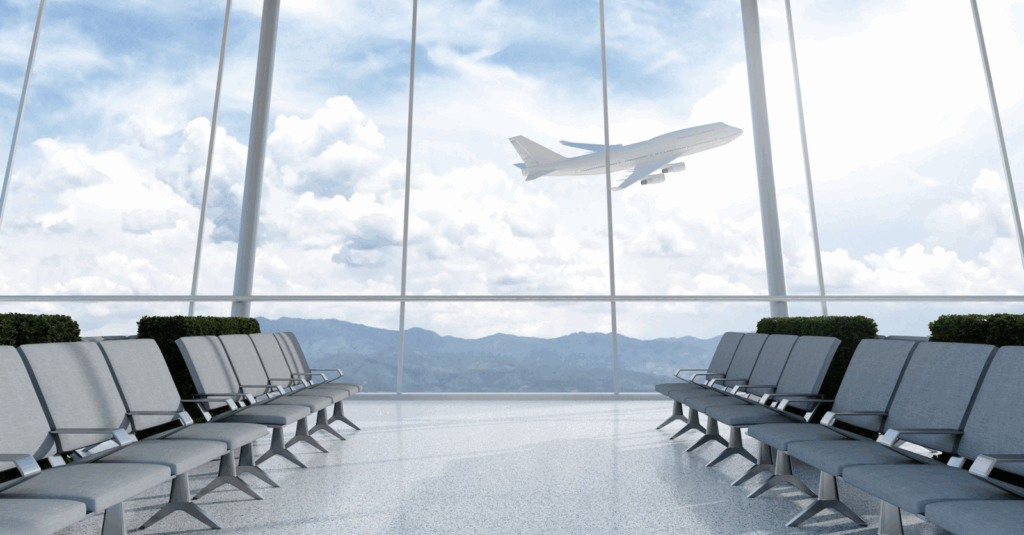 An airport terminal with huge glass windows. An airplane is taking off against a blue sky with cloud.