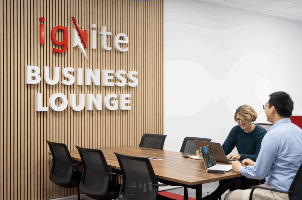 Two Ignite Business Lounge members sat together with their laptops working in the coworking space.